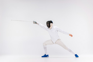 Image showing Man wearing fencing suit practicing with sword against gray