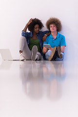 Image showing multiethnic couple sitting on the floor with a laptop and tablet