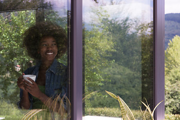 Image showing African American woman drinking coffee looking out the window