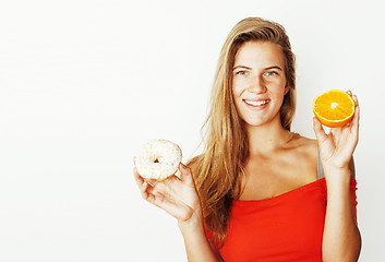 Image showing young blonde woman choosing between donut and apple fruit isolat