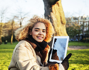 Image showing young cute blond african american girl student holding tablet an