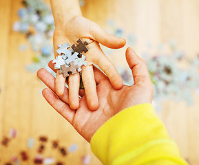 Image showing little kid playing with puzzles on wooden floor together with pa