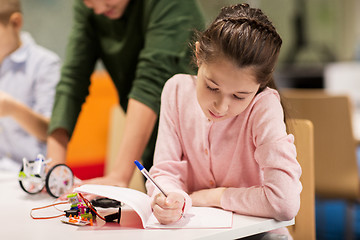 Image showing happy girl writing to notebook at robotics school