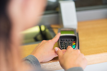 Image showing hand entering pin code to card reader terminal