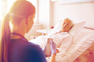 Image showing doctor or nurse visiting senior woman at hospital