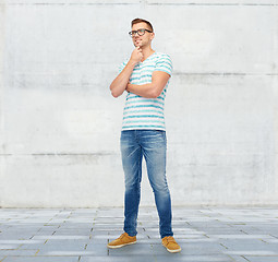 Image showing smiling young man in eyeglasses thinking