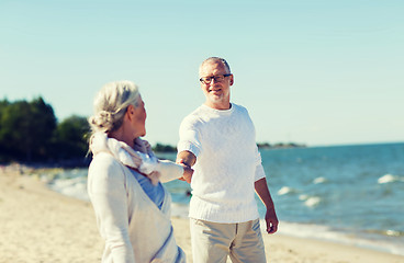 Image showing happy senior couple holding hands on summer beach