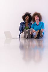 Image showing multiethnic couple sitting on the floor with a laptop and tablet