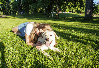 Image showing young attractive blond woman playing with her dog in green park at summer, lifestyle people concept