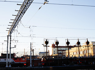 Image showing landscape with railway with trains, lot of steel rafters at sunset