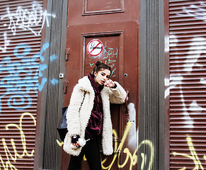 Image showing young pretty stylish teenage girl outside at city wall with graf