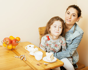 Image showing young mother with daughter on kitchen drinking tea together hugging eating celebration cake on birthday party 