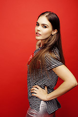 Image showing young pretty emitonal posing teenage girl on bright red background, happy smiling lifestyle people concept