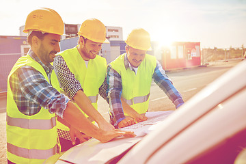 Image showing close up of builders with blueprint on car hood