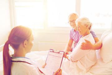 Image showing senior woman and doctor with clipboard at hospital