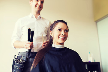 Image showing happy woman with stylist making hairdo at salon