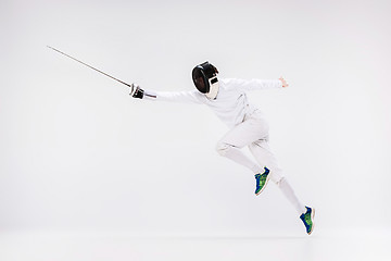 Image showing Man wearing fencing suit practicing with sword against gray