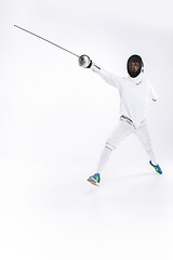 Image showing Man wearing fencing suit practicing with sword against gray