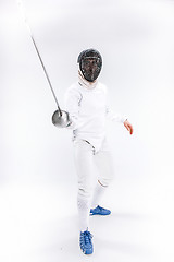 Image showing Man wearing fencing suit practicing with sword against gray