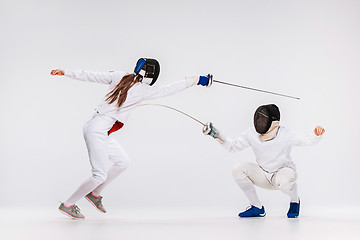 Image showing The men and woman wearing fencing suit practicing with sword against gray