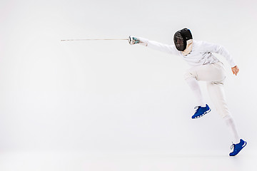 Image showing Man wearing fencing suit practicing with sword against gray