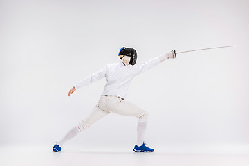 Image showing Man wearing fencing suit practicing with sword against gray