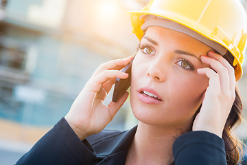 Image showing Worried Female Contractor Wearing Hard Hat on Site Using Cell Ph