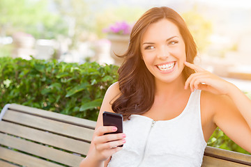 Image showing Smiling Young Adult Female Texting on Cell Phone Outdoors