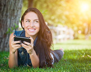 Image showing Mixed Race Young Female Texting on Cell Phone Outside In The Gra