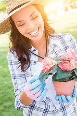 Image showing Young Adult Woman Wearing Hat and Gloves Gardening Outdoors