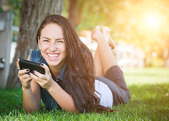 Image showing Mixed Race Young Female Texting on Cell Phone Outside In The Gra