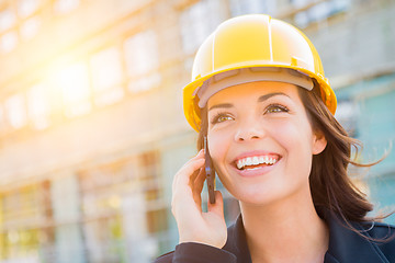 Image showing Young Female Contractor Wearing Hard Hat on Site Using Phone