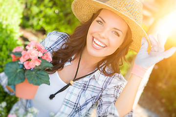 Image showing Young Adult Woman Wearing Hat and Gloves Gardening Outdoors