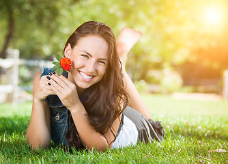 Image showing Attractive Mixed Race Girl Holding Flower Portrait Laying in Gra