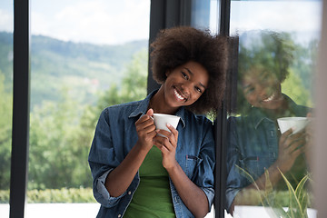 Image showing African American woman drinking coffee looking out the window