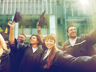 Image showing happy students or bachelors waving mortar boards