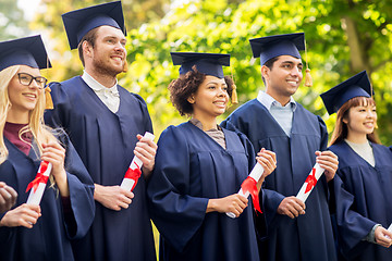 Image showing happy students in mortar boards with diplomas