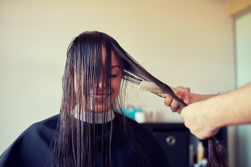 Image showing happy woman with stylist cutting hair at salon