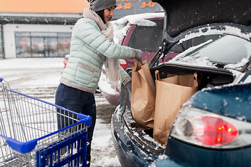 Image showing woman loading food from shopping cart to car trunk