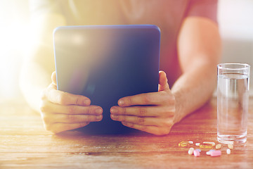 Image showing close up of hands with tablet pc, pills and water