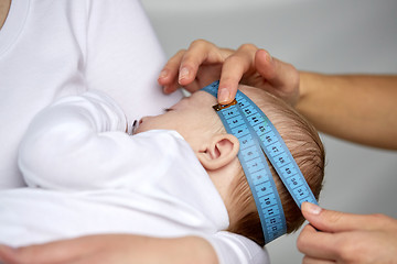 Image showing close up of hands with tape measuring baby head