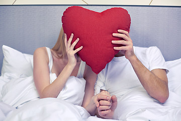 Image showing happy couple in bed with red heart shape pillow