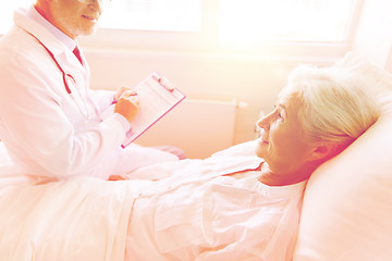 Image showing senior woman and doctor with clipboard at hospital