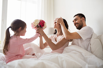 Image showing happy girl giving flowers to mother in bed at home