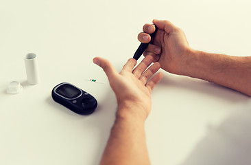 Image showing close up of man checking blood sugar by glucometer