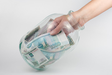 Image showing Hand takes out a three-liter glass jars thousand Russian rubles