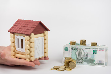 Image showing The hands of toy house standing near the money is to buy housing