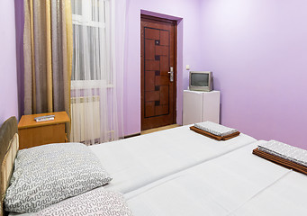 Image showing The interior of a small room with a double bed, a window, a TV and a fridge