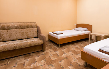 Image showing The interior of a small room with a sofa and two beds