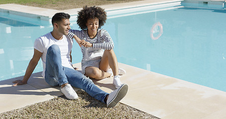 Image showing Young woman relaxing with her boyfriend poolside